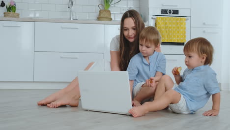 Moderne-Wohnung-Mutter-Und-Zwei-Söhne-Sitzen-Auf-Dem-Boden-Im-Wohnzimmer-Und-Schauen-Auf-Den-Laptop-Bildschirm